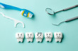 © adragan - Healthy white teeth are smiling and tooth with caries is sad on green mint background. Toothbrush and dentist tools mirror, hook.