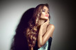 © Subbotina Anna - Sexy young woman portrait. Seductive brunette girl posing in darkness. Beauty glamour lady with long curly hair in spotlight