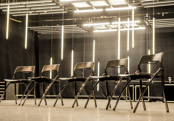 Metal chairs aligned for meeting in  modern business space illuminated with neon lights