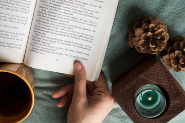 Wall Mural - The cup of tea or coffee with a book and candle on the wooden table near the window on the rainy weather.