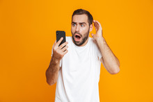 Photo Of Terrified Man 30s In Casual Wear Looking At Mobile Phone With Fear, Isolated Over Yellow Background