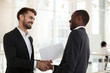 © fizkes - Positive diverse businessmen shaking hands before negotiating
