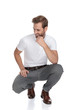 lughing crouched smart casual man thinks and looks to side
