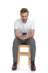 Wall Mural - casual man reading on his phone while sitting