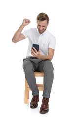 Poster - seated casual man reading good news on his mobile phone