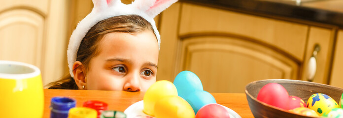 Wall Mural - Having fun on Easter egg hunt. Child girl wearing bunny ears and painting eggs. colorful eggs.