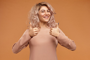 Wall Mural - You did good job! Confident successful young woman with stylish hairdo smiling broadly, making thumbs up sign with both hands, saying Well done, appraising nice movie, giving it high rating