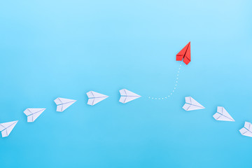 Wall Mural - Business for new ideas creativity, innovative and solution concepts. Group of white paper plane in one direction and one red paper plane pointing in different way on blue background. copy space