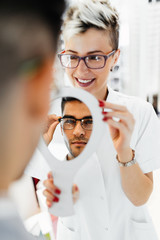 Wall Mural - Young optometrist helps customer to choose right eyeglasses