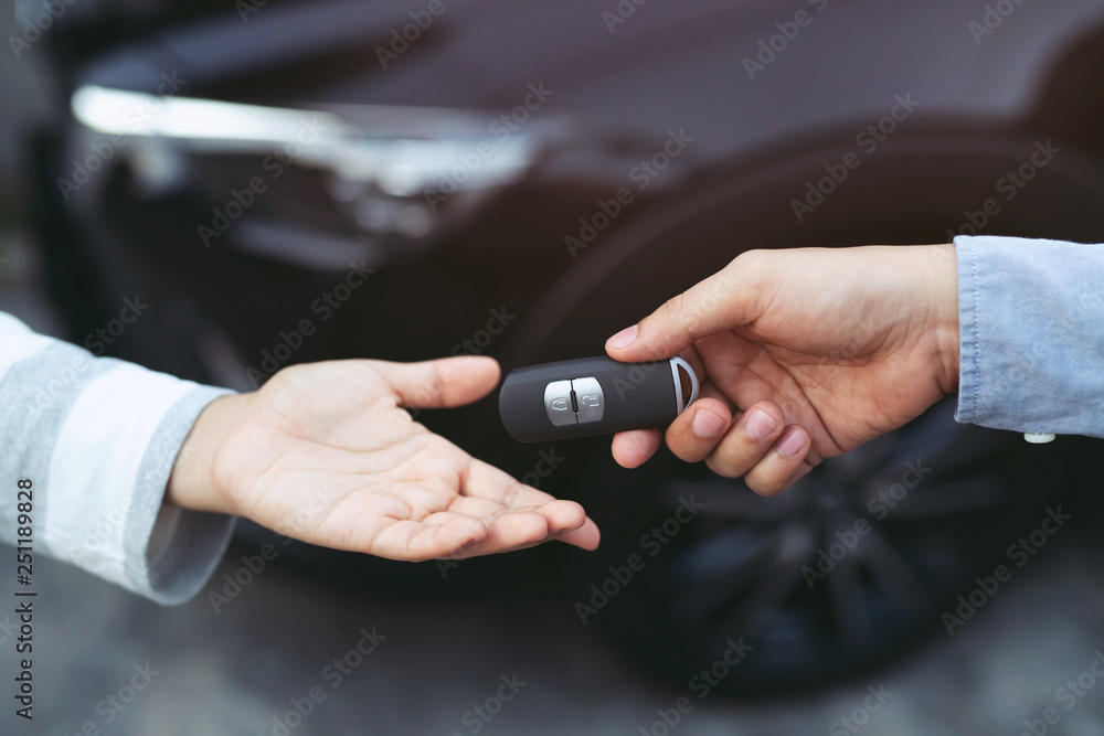 businessman exchange handing over the car keys for to a young women. - obrazy, fototapety, plakaty 