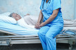 © amazing studio - Asian nurse physiotherapist doctor care, help and support senior or elderly old lady woman patient lie down in bed at hospital ward : healthy strong medical concept.