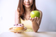 © Kittiphan - Woman making decision between healthy food and unhealthy food, Healthy and diet lifestyle concept