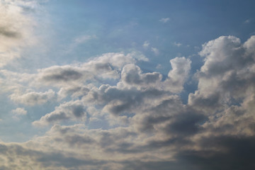 Scattered Cumulus clouds in the evening blue sky. Rain clouds are coming and foretell a change of weather. Meteorology and weather forecast. Background, backdrop or Wallpaper.