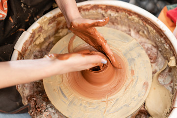 Craftsman hands making pottery bowl. Woman working on potter wheel . Family business shop sculpts pot from clay view top.