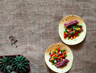Wall Mural - Traditional dish of Mexican cuisine. Corn tortilla tacos with vegetable filling on  burlap texture. 