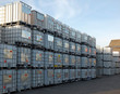 used metal framed intermediate bulk containers stacked on pallets waiting to be cleaned or recycled in an industrial yard