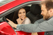 © Nestor - View of gorgeous brunette girl sitting inside vehicle, enjoying comfortable seats and listening instructor. Handsome manager of car dealership presenting characteristics of automobile to female.