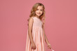 © nazarovsergey - Little girl with a blond curly hair, in a pink dress is posing with a candy