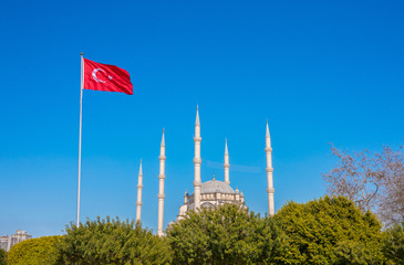 Wall Mural - Mosque and Turkish flag. Turkish flag  waving at blue sky with mosque minarets. Turkish islamic republic country. Travel to Turkey. 