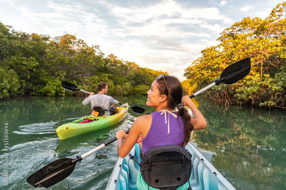 Couple kayaking together in mangrove river of the Keys, Florida, USA. Tourists kayakers touring the river of Islamorada. - obrazy, fototapety, plakaty 