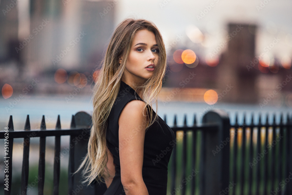Beautiful woman with long blond hair walking in the city at evening ...