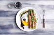 © Pixel-Shot - Plate with bacon wrapped asparagus and egg on wooden table
