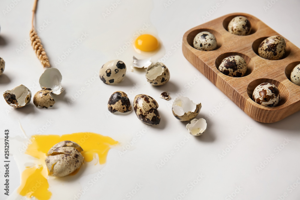 Broken raw quail eggs on white background