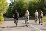 Fototapeta  - three girls and one guy ride bicycles outdoors, outdoor activities, lifestyle, concept of sport