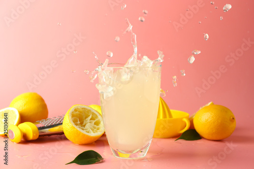 Fotografía Glass of tasty cold lemonade with splashes on color background