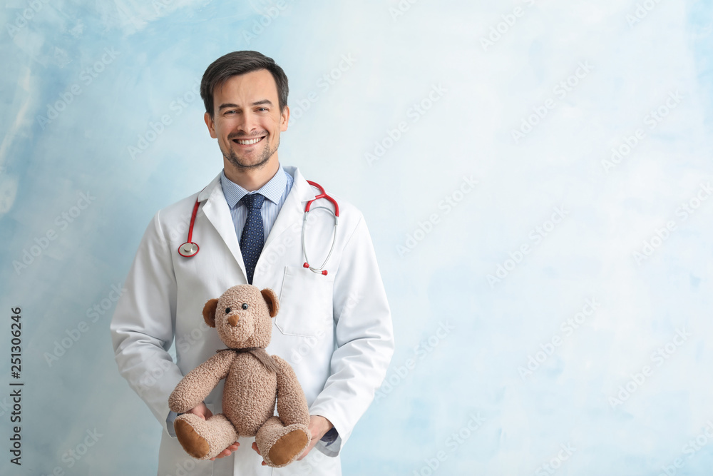 Pediatrician with toy bear on color background