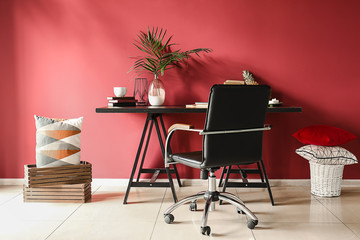 Dark table with comfortable armchair near color wall in room