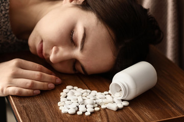 Wall Mural - Young unconscious woman with pills on table. Suicide concept