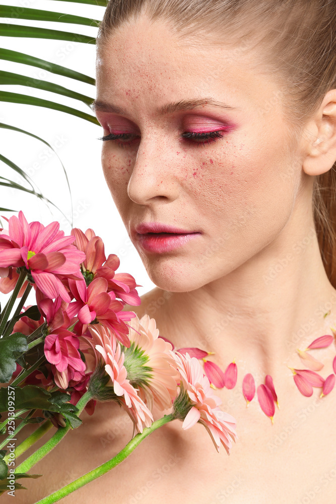 Beautiful woman with creative makeup and flowers on white background