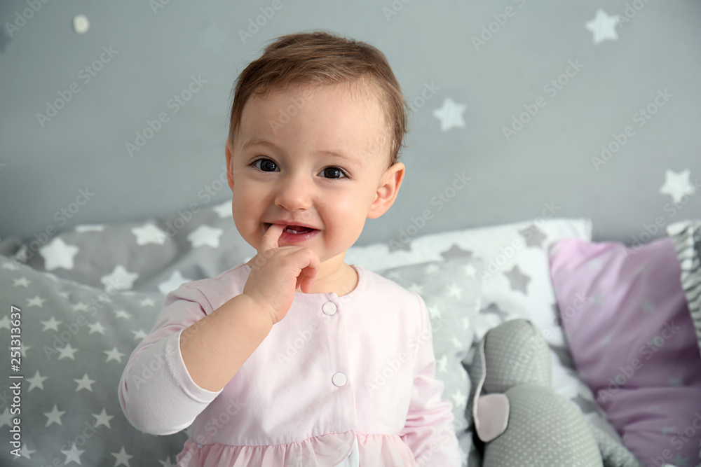 Cute baby girl sitting on bed
