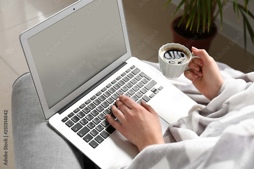 Young woman working on laptop and drinking coffee at home