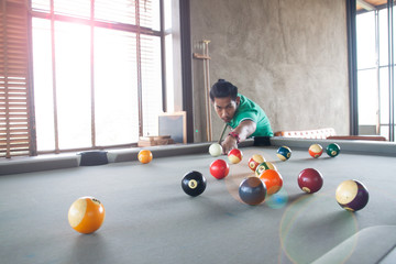 Handsome asian young man playing pool at home, Selective focus on ball