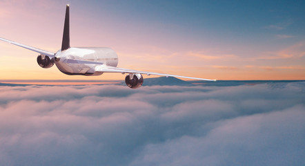 Commercial airplane jetliner flying above dramatic clouds in beautiful sunset light. Travel concept.