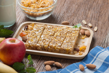 Homemade Cereal granola bars with nuts and garnola, milk bottle, apple, banana on wooden desk, Energy food, Healthy snack.