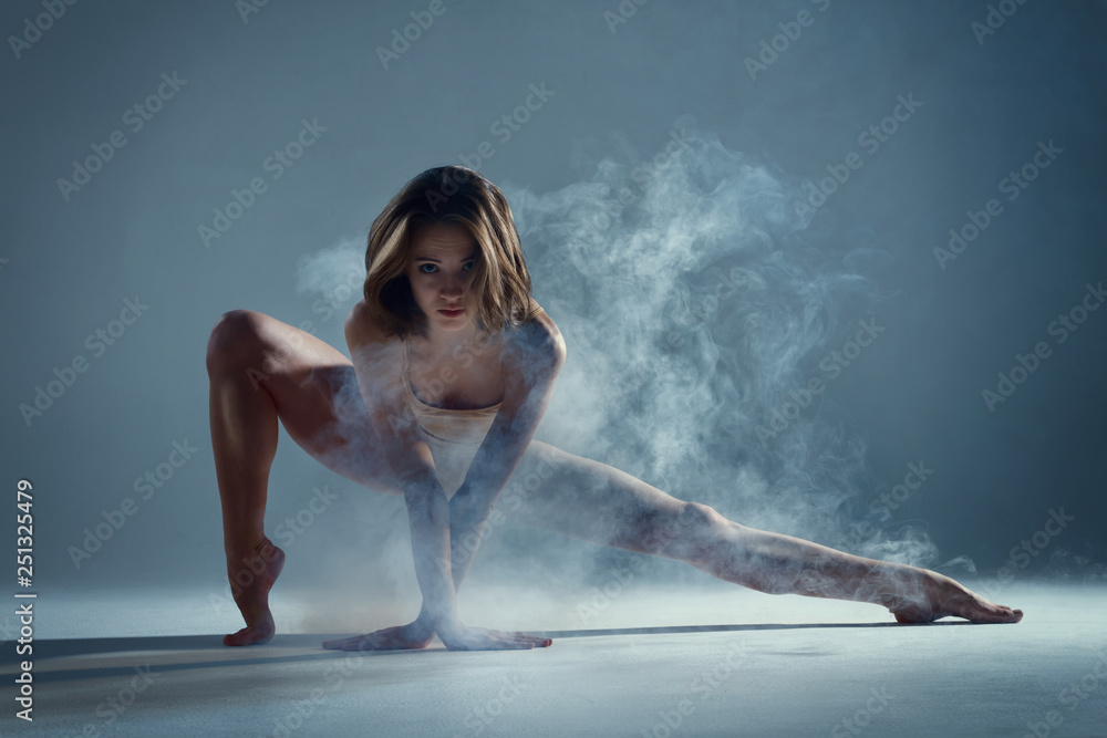 Dancing in cloud concept. Muscle brunette beauty female girl adult woman dancer athlete gymnast in smoke fog wearing dance bodysuit jumping in mid air, performance on isolated grey / black background - obrazy, fototapety, plakaty 