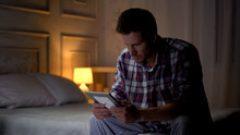 Unhappy Lonely Young Male Sitting On Bed Looking At Photo, Breakup, Missing Wife