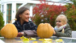 © motortion - Cheerful girl and mom painting scary face on pumpkin, spend time together, fun
