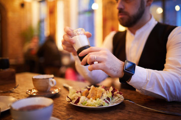 Wall Mural - Close up of unrecognizable businessman wearing smartwatch eating salad in cafe during lunch, copy space