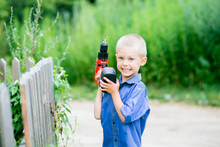 Little Blond Boy Of Five Years Old With Blue Eyes On The Street With A Screwdriver / Drill