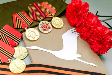 Wall Mural - Only EDITORIAL. Moscow, RUSSIA, May 9, 2017: Military cap, red carnations and St. George ribbon on wooden background/St. George ribbon - the symbol of the great Victory/Victory Day