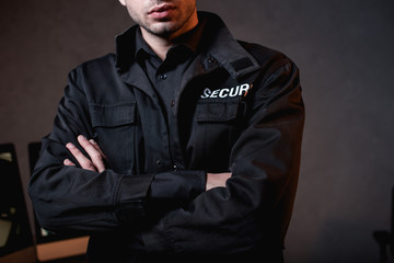 Wall Mural - cropped view of guard in uniform with crossed arms at workplace