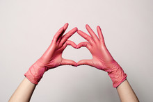 Closeup Of A Hand In Latex Rubber Medical Pink Gloves Folded Into A Heart Sign. Isolated On White Background. Concept Love Couple Couple Valentine