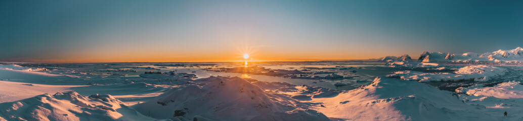 Poster - Bright colorful sunset panorama view in Antarctica. Orange sun lights over the snow covered polar surface. Picturesque winter landscape. The beauty of the wild untouched Antarctic nature.