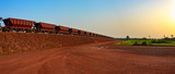 Fototapeta Desenie - Railway carriages for transportation of bauxite ore on train tracks at the end of the railway line from bauxite mining. Guinea, Africa.