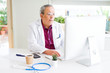 © Krakenimages.com - Handsome senior doctor man doing research using laptop looking for a cure at the clinic with a confident expression on smart face thinking serious