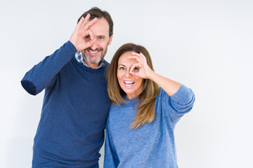 Poster - Beautiful middle age couple in love over isolated background doing ok gesture with hand smiling, eye looking through fingers with happy face.